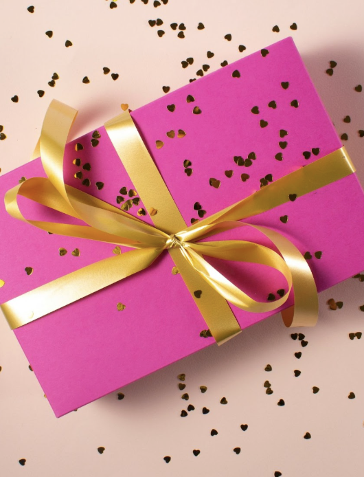 Bright pink gift box with a gold ribbon and heart confetti. A fun, memorable realtor closing gift your clients will love.